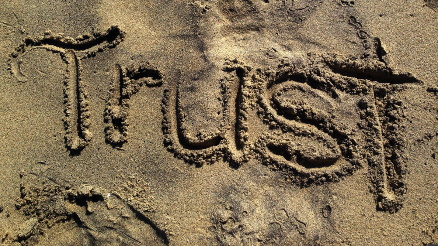 Das englische Wort für Vertrauen "Trust" in den Sand geschrieben