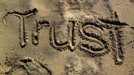 Das englische Wort für Vertrauen "Trust" in den Sand geschrieben